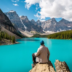 Man sitting on rock looking at the BANFF mountain range